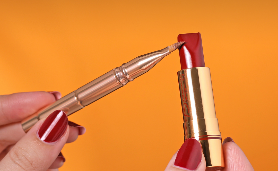 Hand's Holding Bésame Cosmetics Red Lipstick and Makeup Brush
